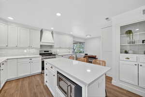 Kitchen featuring gas range, light stone countertops, light wood-style floors, white cabinets, and recessed lighting