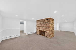 Basement with wainscoting, baseboard heating, light colored carpet, recessed lighting, and a decorative wall