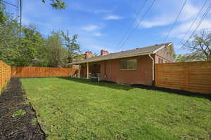 Rear view of property featuring a chimney, brick siding, a fenced backyard, and a patio