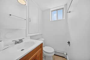 Half bath featuring vanity, baseboard heating, and light tile patterned floors