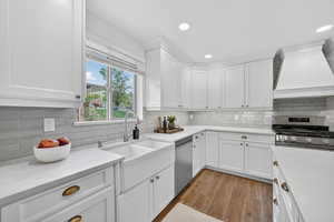 Kitchen featuring stainless steel appliances, light wood finished floors, white cabinetry, recessed lighting, and light stone counters