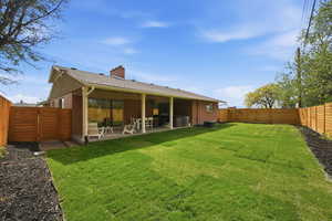 Rear view of house with a patio, a fenced backyard, a chimney, brick siding, and a shingled roof