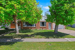 Obstructed view of property with a front yard, driveway, brick siding, and a garage