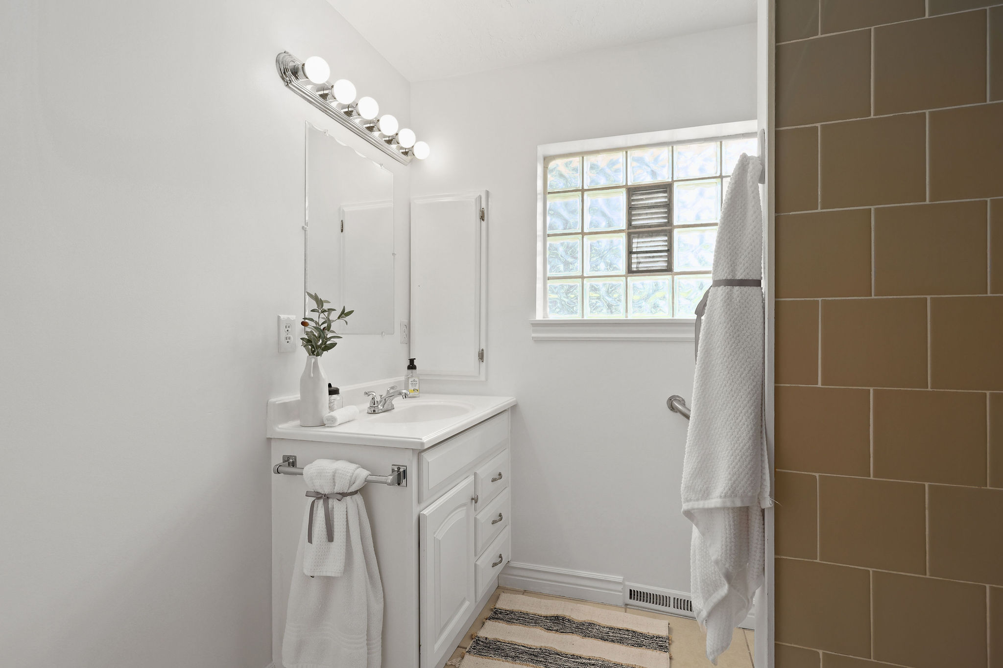 Bathroom vanity featuring white cabinetry, a single basin sink, and a chrome faucet