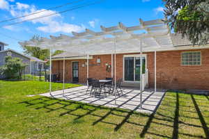 Rear view of house with a pergola, a patio area, and brick siding