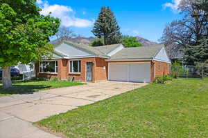 Ranch-style house with a mountain view, concrete driveway, brick siding, an attached garage, and a tiled roof