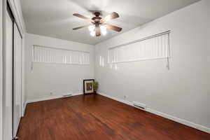 Unfurnished bedroom with dark wood-type flooring, a ceiling fan, and a closet