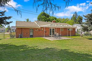 Rear view of property with a gate, a patio area, brick siding, and a chimney