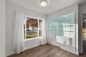 Unfurnished dining area featuring dark wood-style floors and baseboards