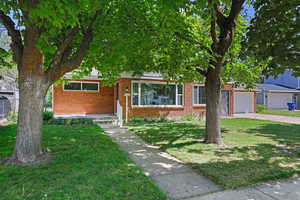 View of front of property featuring an attached garage, a front yard, brick siding, and driveway