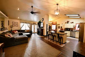 Living area with a ceiling fan, a fireplace, hanging lights, lofted ceiling, and healthy amount of natural light