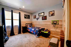 Carpeted bedroom featuring a wainscoted wall, recessed lighting, and wooden walls