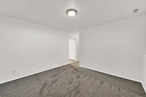 Empty room with arched walkways and dark carpet