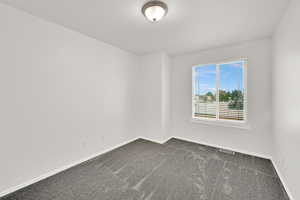 Empty room featuring dark carpet and baseboards