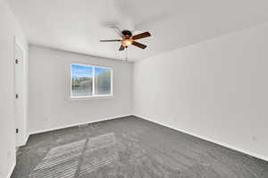 Empty room featuring dark carpet and ceiling fan