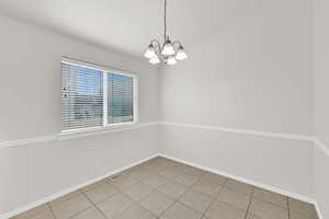 Unfurnished dining area with a chandelier and light tile patterned flooring