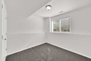 Empty room with dark carpet and baseboards