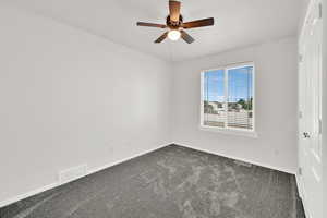 Unfurnished room featuring dark carpet and ceiling fan