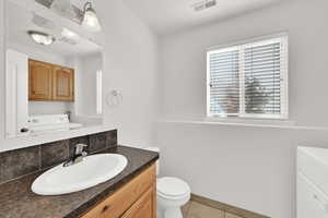 Half bathroom with vanity, light tile patterned floors, and washer / clothes dryer