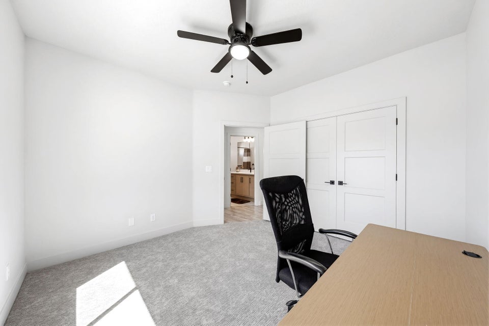Office with light carpet and a ceiling fan
