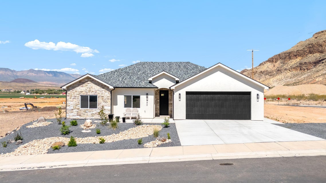 Single story home with a mountain view, an attached garage, concrete driveway, stone siding, and stucco siding
