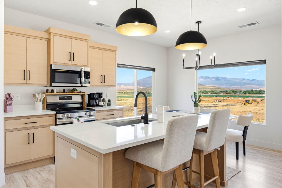 Kitchen featuring light wood finish cabinets, stainless steel appliances, a center island with sink, a breakfast bar, and light wood finished floors