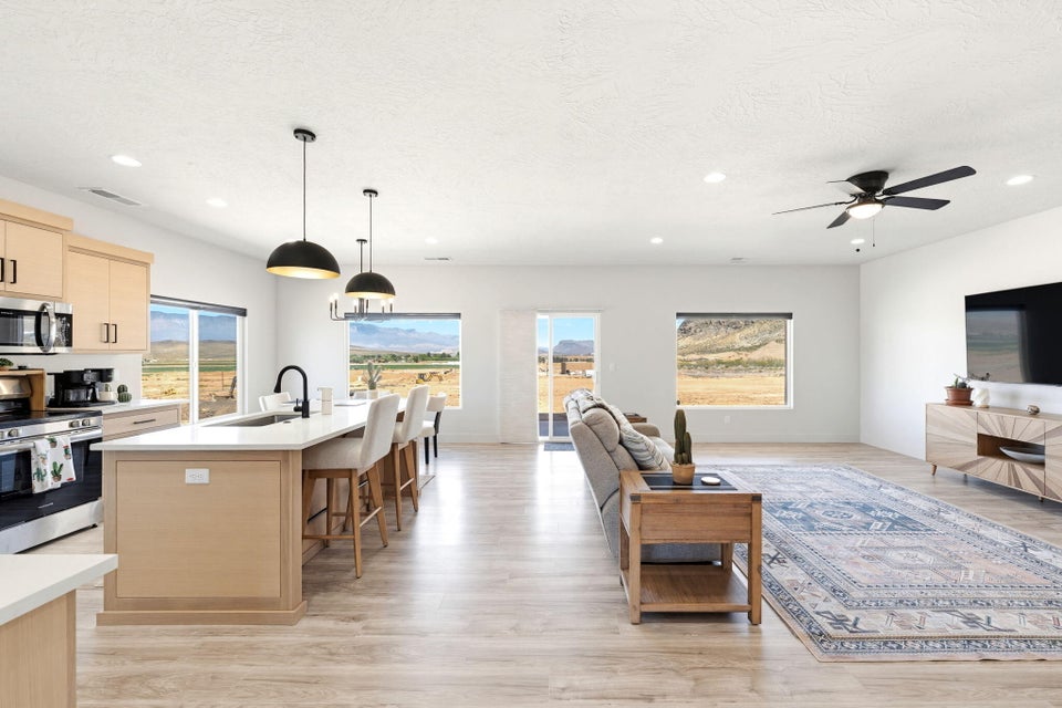 Living area featuring light wood-style flooring, a ceiling fan, and recessed lighting