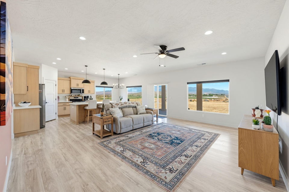 Living area with a chandelier, light wood-style floors, plenty of natural light, and ceiling fan