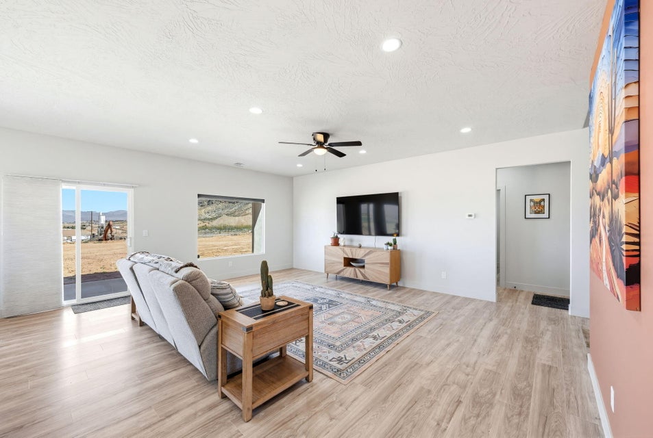 Living room with light wood finished floors, ceiling fan, recessed lighting, and a textured ceiling