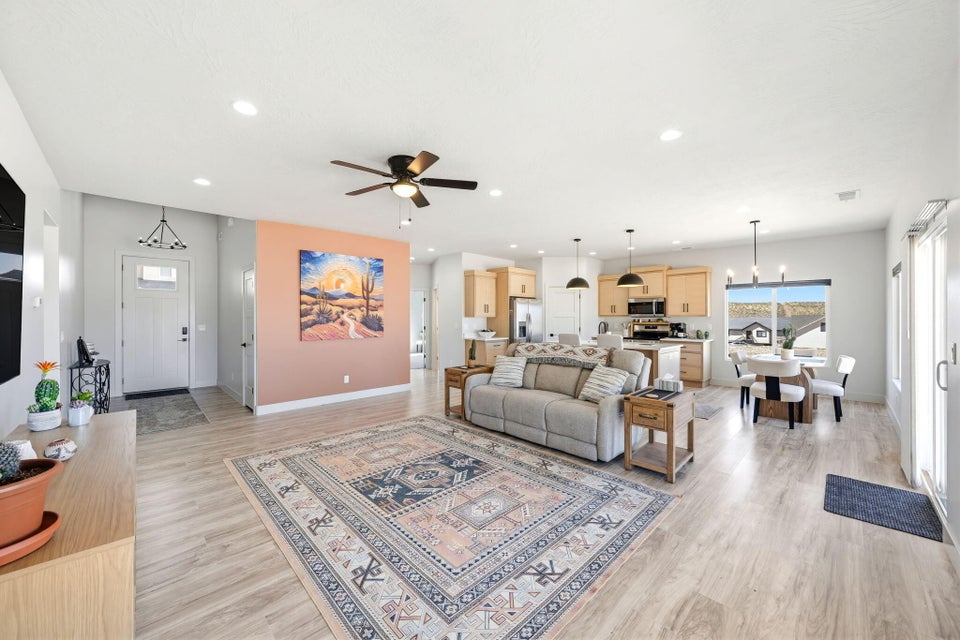 Living area featuring light wood-style floors, ceiling fan, and hanging lights