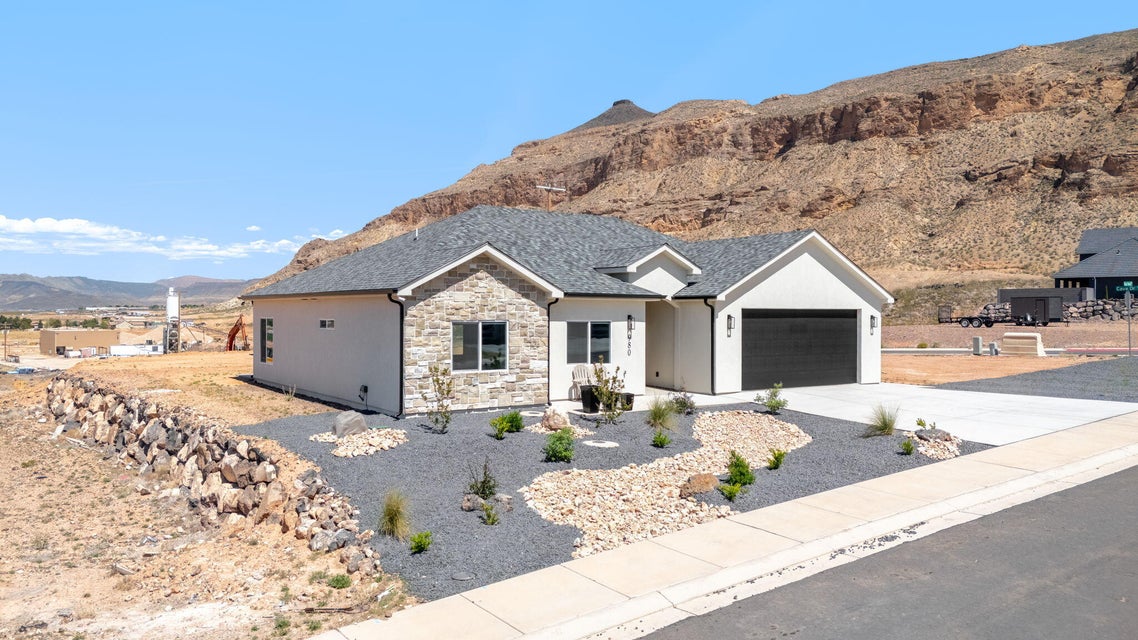 View of front facade with a mountain view, concrete driveway, a garage, and stone siding