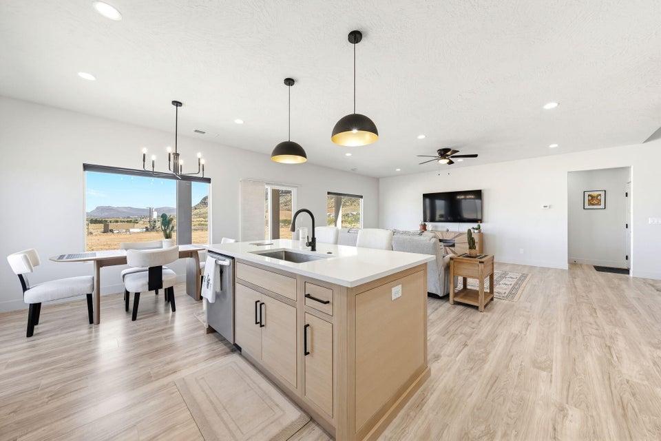 Kitchen with a center island with sink, open floor plan, light wood finish cabinetry, and light wood finished floors