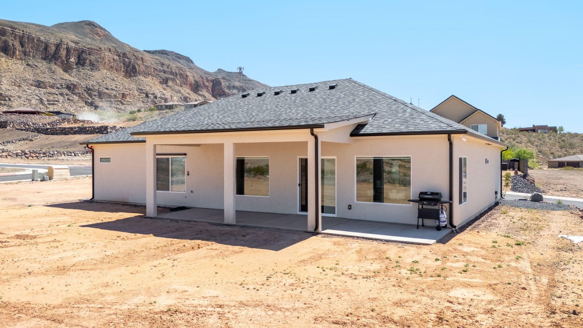 Back of property with a patio, a shingled roof, stucco siding, and a mountain view