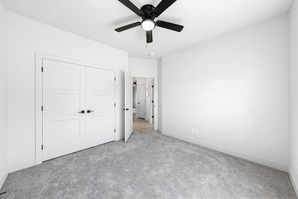 Unfurnished bedroom with light carpet, ceiling fan, and a closet
