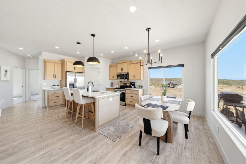 Kitchen with light wood finish cabinetry, a kitchen breakfast bar, stainless steel appliances, light wood-style floors, and an island with sink
