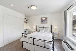 Bedroom featuring dark carpet, a ptac unit, and a closet