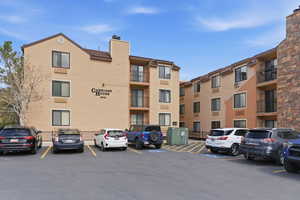 View of apartment building / complex featuring uncovered parking