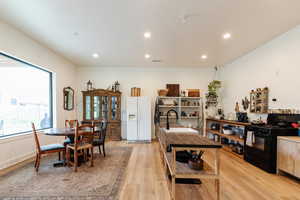 Kitchen featuring black range with gas stovetop, white fridge with ice dispenser, light wood-style flooring, wooden counters, and recessed lighting