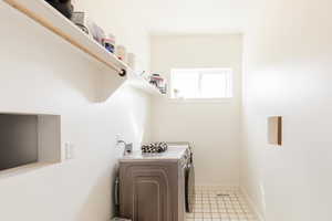 Laundry area with washing machine and clothes dryer and light tile patterned flooring