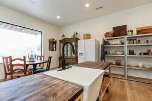 Kitchen featuring butcher block counters, white refrigerator with ice dispenser, light wood-style floors, and recessed lighting