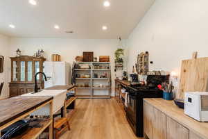 Kitchen with wood counters, black gas range, white fridge with ice dispenser, light wood-style floors, and recessed lighting