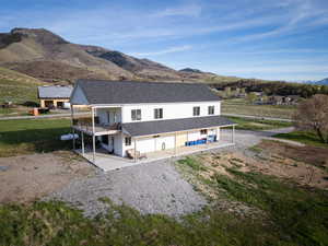 Rear view of property with a mountain view, a shingled roof, covered porch, a yard, and a balcony