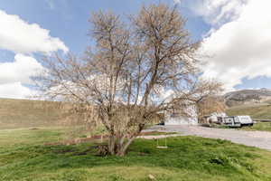 View of green lawn featuring gravel driveway, a mountain view, and a garage
