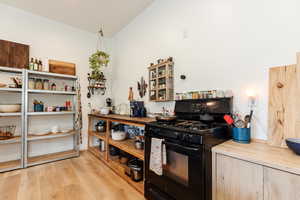 Kitchen with black gas stove, light wood-type flooring, butcher block counters, and light wood finish cabinets