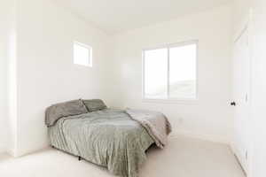 Bedroom featuring light carpet and baseboards