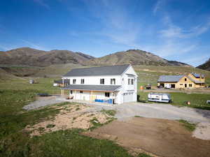 View of front of property with an attached garage, a mountain view, gravel driveway, and a porch