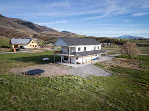 Rear view of house with a trampoline, a patio, a mountain view, a balcony, and roof with shingles