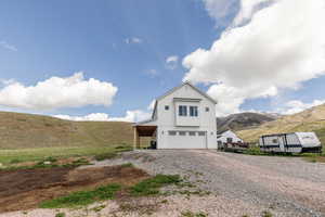 View of front of home with a mountain view, an attached garage, and gravel driveway