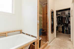 Bathroom featuring a walk in closet and a bath