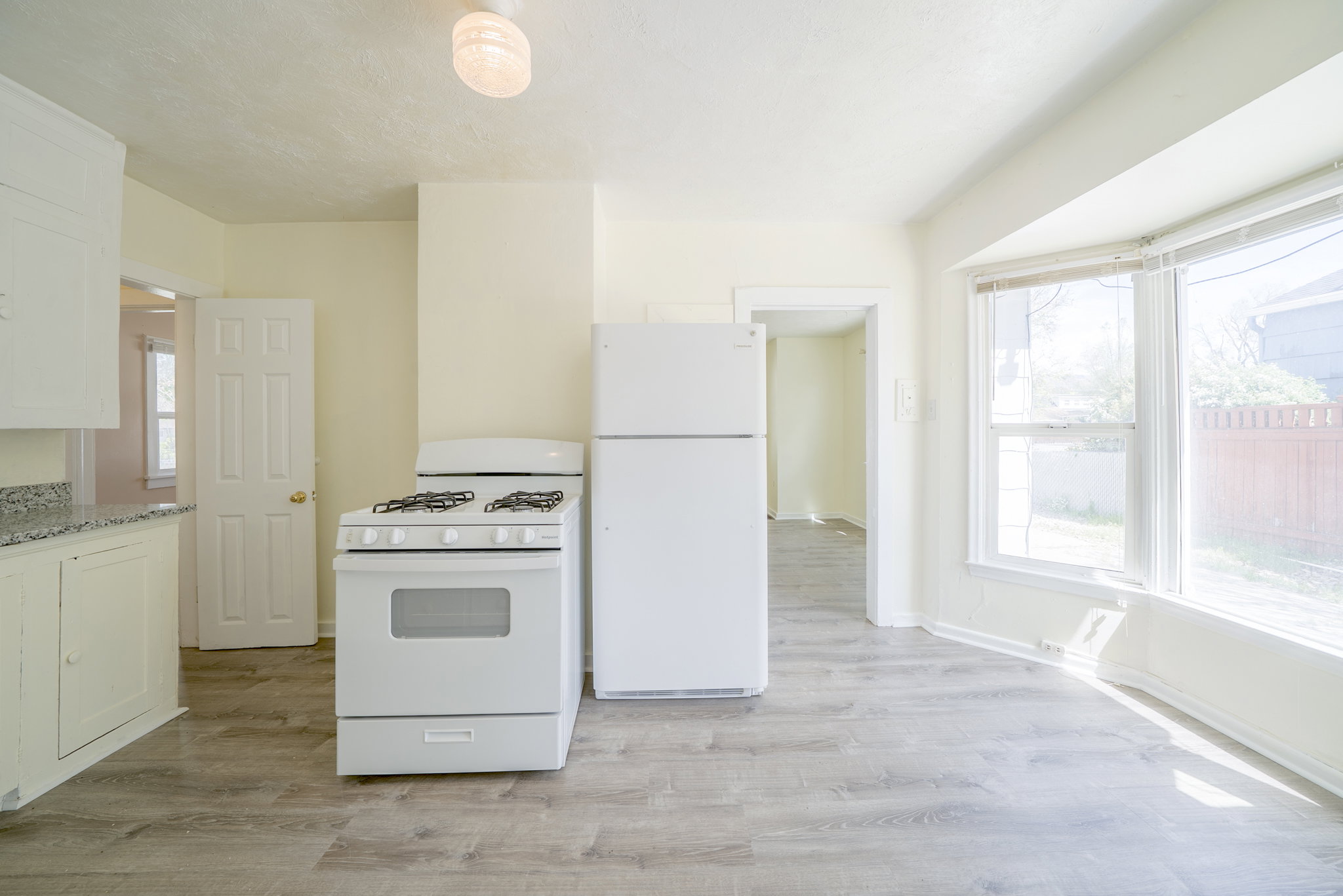 Kitchen with white appliances, light wood finished floors, and white cabinets
